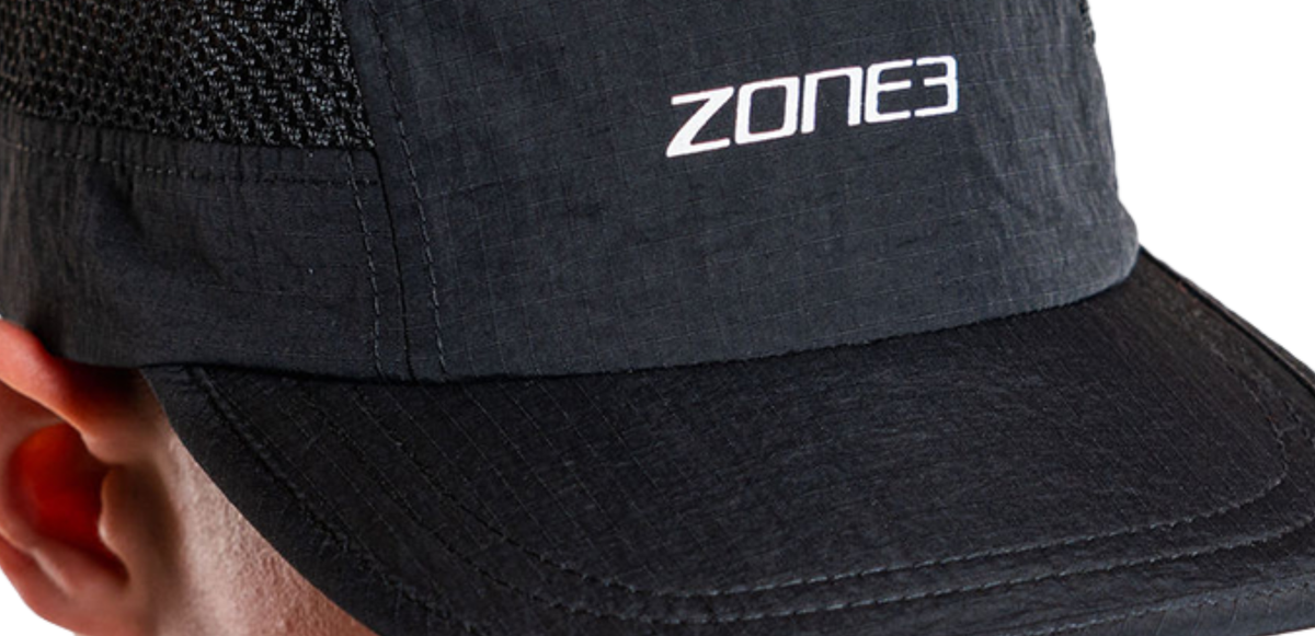 Close up of black mesh running cap with 'Zone3' logo worn by a person, on a white background