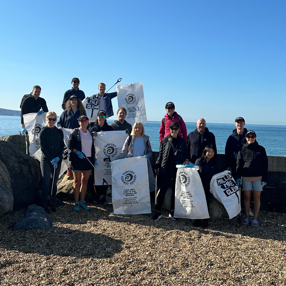 A group of ZONE3 employees holding waste sacks and litter pickers. They are all smiling at the camera