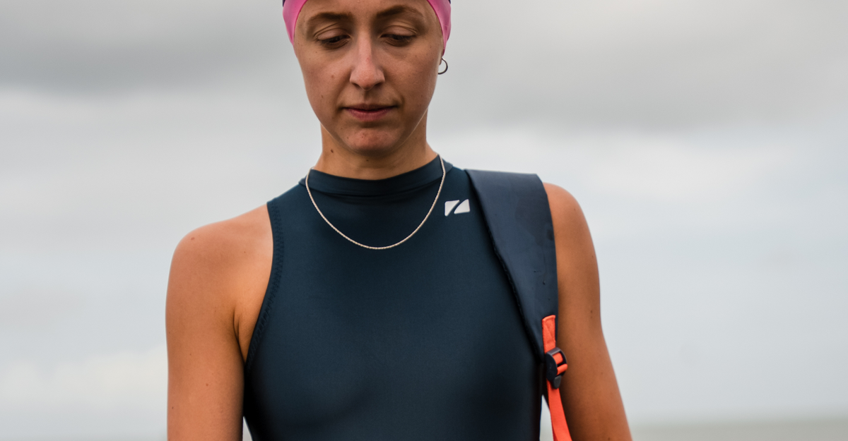 Person in Zone3 TI+ high neck thermal swimsuit and swim cap with a blurred background