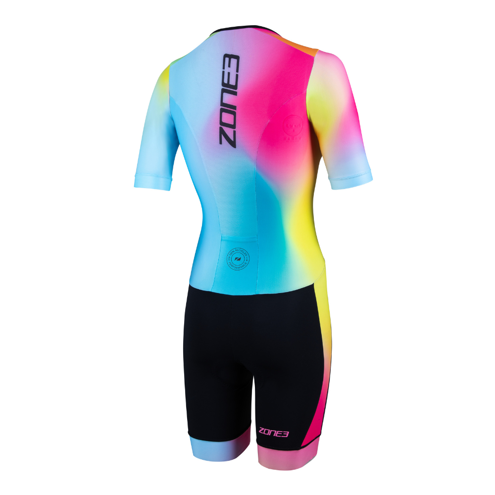 Vista trasera del trisuit Activate+ de manga corta para mujer de ZONE3, con el logotipo vertical de ZONE3 y un colorido degradado en la parte superior. El short es negro, con una pequeña etiqueta circular reciclada en la zona lumbar.