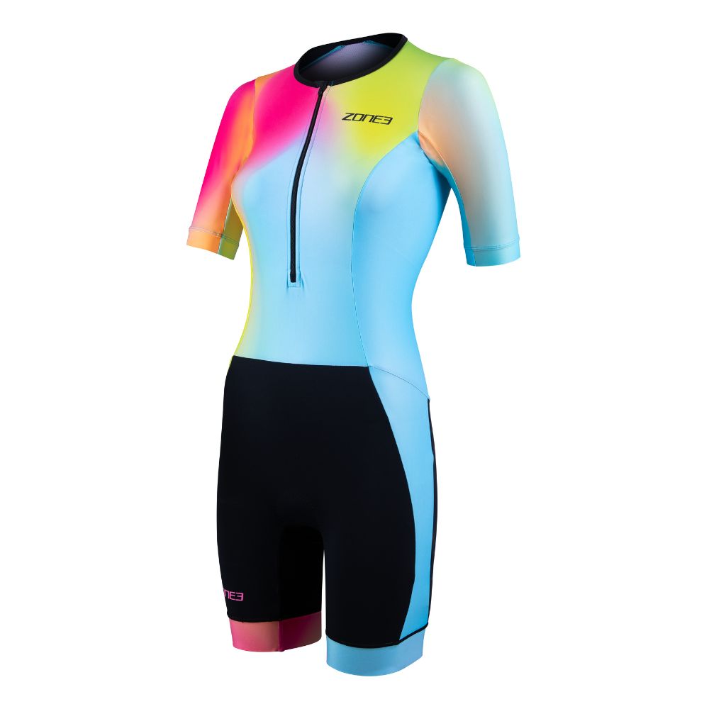 Vista frontal del trisuit Activate+ de manga corta para mujer de ZONE3, con diseño degradado en rosa, amarillo y azul. Cuenta con cremallera frontal y sección de short en negro.