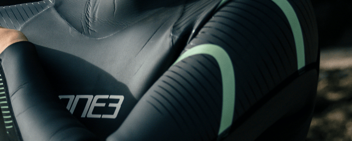 Close-up of a person wearing a wetsuit with '3E' branding on the sleeve.