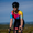 Primer plano frontal de una ciclista con el trisuit Activate+ de manga corta para mujer de ZONE3. Los colores degradados en azul, rosa, amarillo y naranja son visibles bajo la luz del sol.