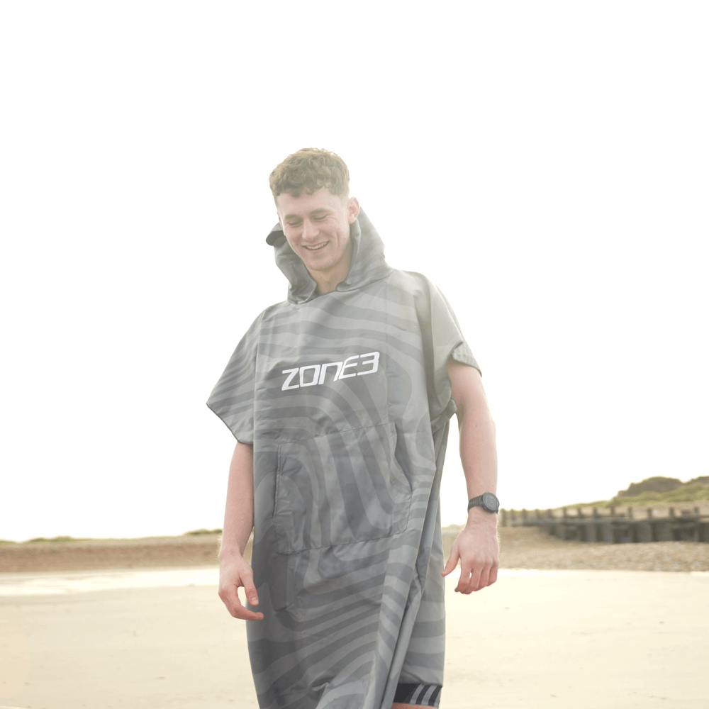 Hombre con el albornoz de microfibra en la playa, mostrando su ligereza y secado rápido.